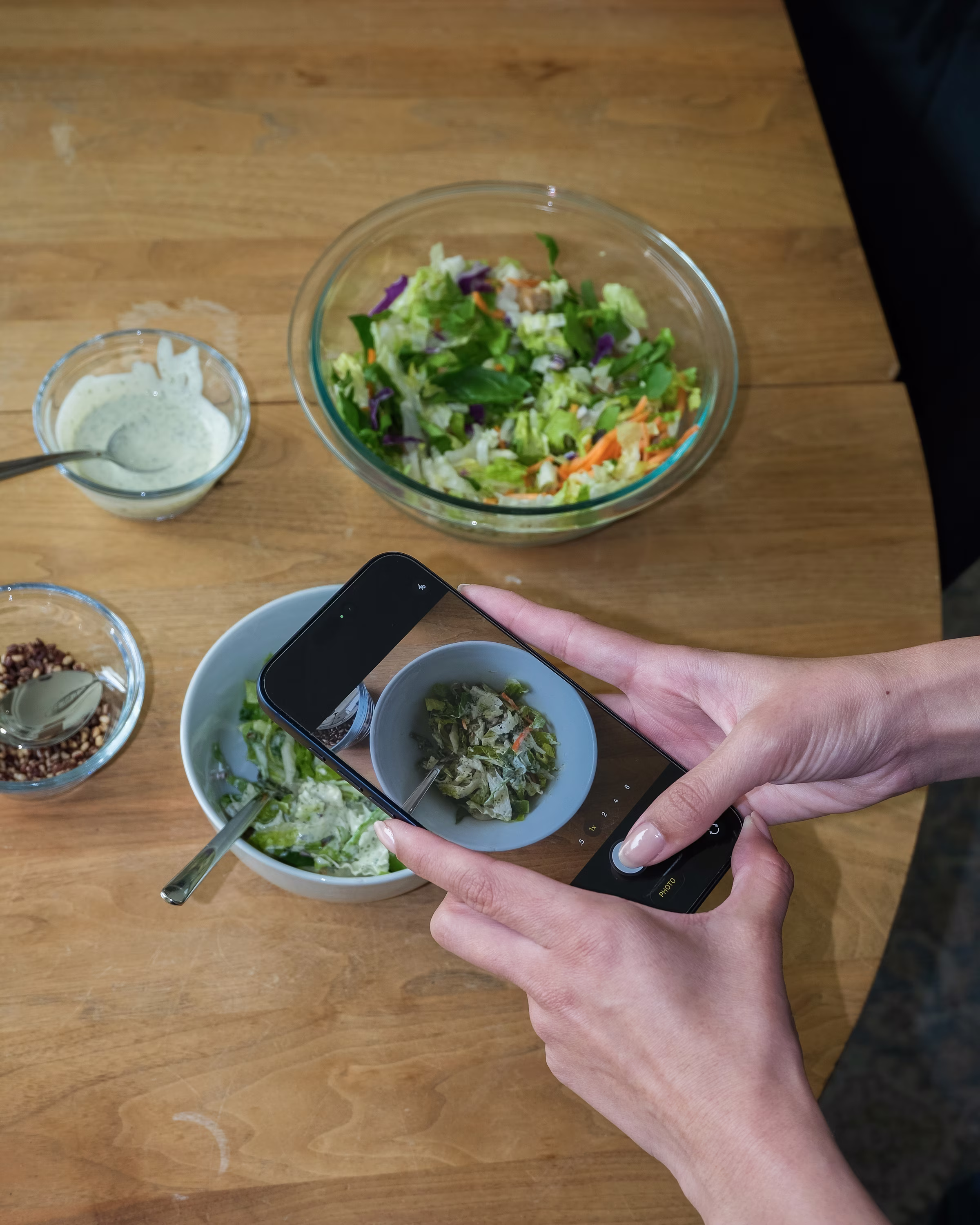 A person photographing a salad with a phone